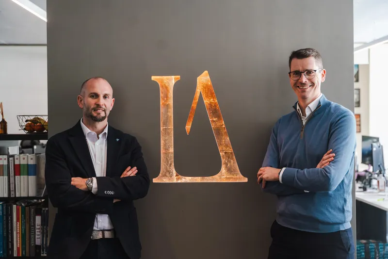 Chris and Andrew have their portrait taken standing in front of the LA London sign